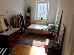 a bedroom with a bed, dresser and mirror in it next to a large window