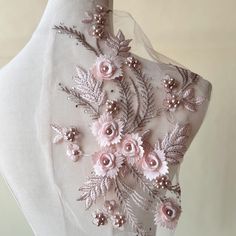 a white mannequin with pink flowers on it's chest and some pearls