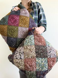 a woman holding a multicolored crocheted bag