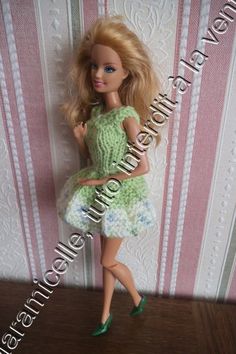 the doll is wearing a green dress and shoes