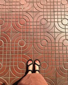 a person standing on a tile floor with their feet propped up against the ground and wearing sandals