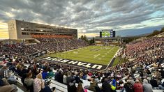 a stadium full of people watching a football game on the field at sunset or dawn