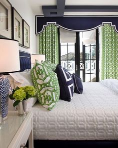 a bedroom with green and blue decor on the walls, white bedding, and black framed windows