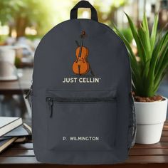 a backpack with a cello on it sitting next to a potted plant