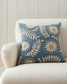 a blue and white pillow sitting on top of a couch next to a white chair