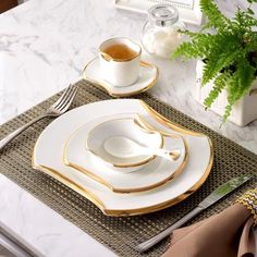 there is a place setting on the table with gold trimmings and white dishes