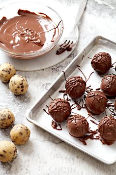 chocolate truffles on a baking sheet and in front of a bowl of melted chocolate