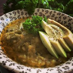 a bowl filled with soup and sliced avocado