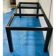 a metal frame is sitting on the floor in front of a white wall and blue tarp