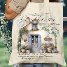 a woman carrying a tote bag with an image of a house and potted plants