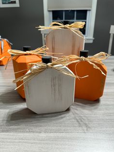 four orange and white vases sitting on top of a wooden table