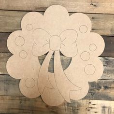 a paper cut out of a flower with a bow on it's head, hanging from a wooden wall