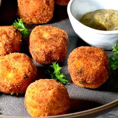 several fried food items on a plate with dipping sauce in a bowl next to them