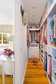 a walk - in closet with white shelving and shelves filled with baby's clothes