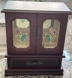 a wooden cabinet with stained glass doors on the top and bottom, sitting on a marble countertop