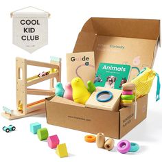 an open cardboard box filled with toys on top of a white table next to a banner