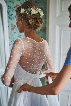 the back of a woman's wedding dress with flowers in her hair