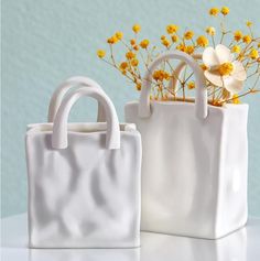 two white bags with flowers in them sitting on a table