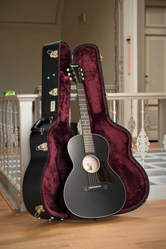 an acoustic guitar and case sitting on the floor in front of a stair banister