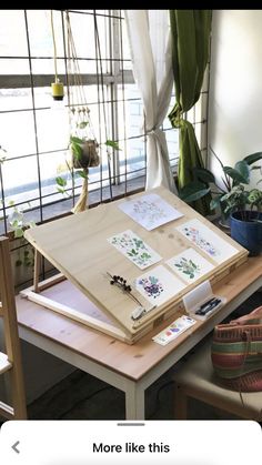 a wooden table topped with lots of pictures and plants in front of a large window