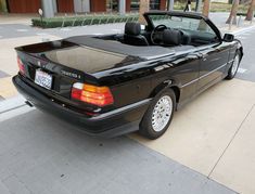 a black convertible car parked on the side of the road in front of a building