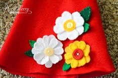 a close up of a red dress with flowers on it and buttons in the center