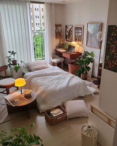 a bedroom with two beds, desks and plants in the corner on the floor