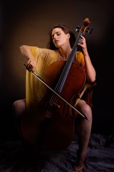 a woman sitting on a chair holding a cello