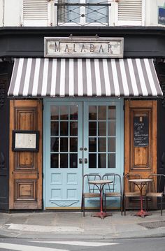 a restaurant with blue doors and striped awnings