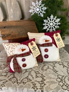 two snowman pillows sitting on top of a table next to a christmas tree and wooden box