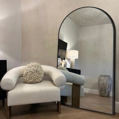 a white chair sitting in front of a large mirror