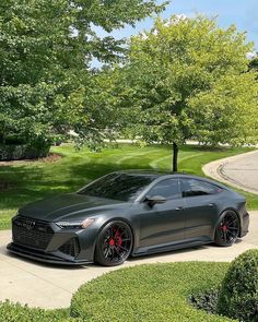 a grey car parked on the side of a road next to some bushes and trees