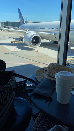 an airplane sitting on the tarmac at an airport with its windows open and coffee cups in front of it