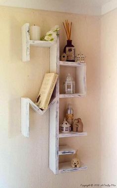 a shelf with books and candles on it in the corner of a room next to a wall