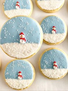 decorated cookies with frosting and snowmen in the middle are arranged on a white surface