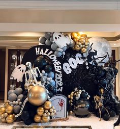 a halloween display with balloons and decorations on the wall in front of it is black, gold and white