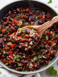 a wooden spoon in a pot filled with black beans