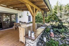 an outdoor kitchen and dining area on a deck with wood flooring, covered in stone