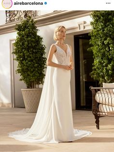 a woman in a white wedding dress standing on a patio with her back turned to the camera