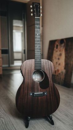 an acoustic guitar sitting on top of a wooden floor