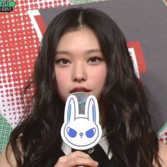 a girl with long black hair holding a microphone in front of her face and wearing bunny ears