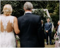 a man in a suit standing next to a woman at a wedding ceremony with other people