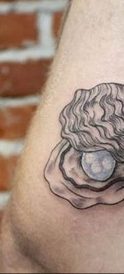 a close up of a person's leg with a tattoo on it that has an image of a shell