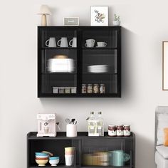 a black shelf with dishes and cups on it next to a white couch in a living room