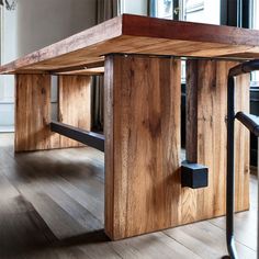 a wooden table sitting on top of a hard wood floor next to a metal railing