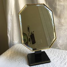 a mirror sitting on top of a table next to a white bed covered in sheets