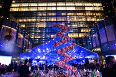 people are gathered around a bar with flowers on the top and an upside down glass structure