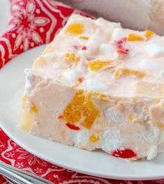 a white plate topped with a piece of cake next to a red and white napkin