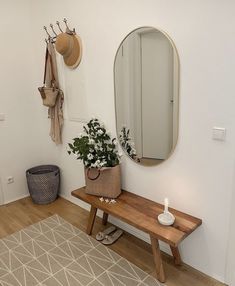 a wooden bench sitting next to a mirror and potted plant on top of it