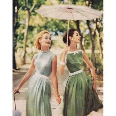 two women in green dresses holding an umbrella